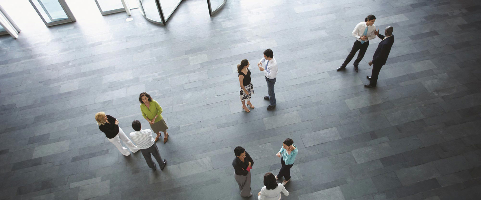 Geschäftsleute stehen in kleinen Gruppen in einer Eingangshalle zusammen und unterhalten sich